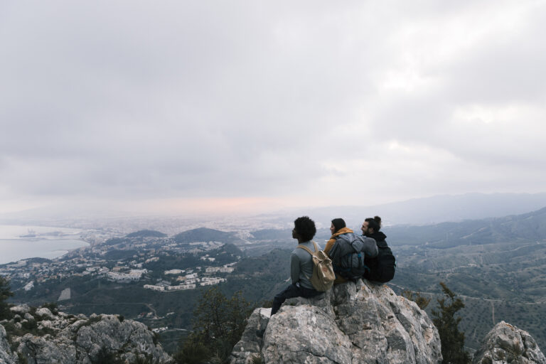 Curated Travel 22 three-friends-sitting-top-mountain-enjoying-scenic-view