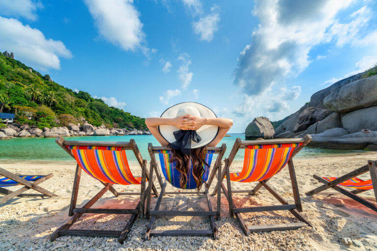 Experiential Travel 14 Woman with hat sitting on chairs beach in beautiful tropical beach. Woman relaxing on a tropical beach at Koh Nangyuan island.